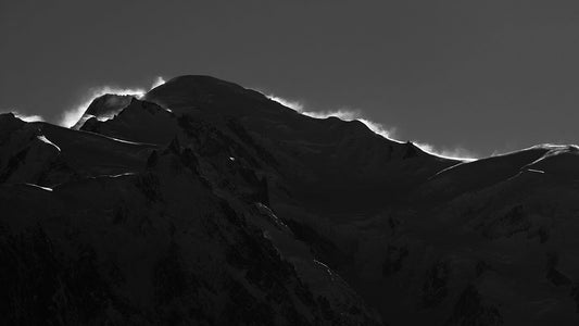 Backlit by the sun, the Mont Blanc massive combines with wind blown snow to silhouette its form, leaving the viewers imagination to fill the detail of the dramatic scene hidden in the shadows of this photograph