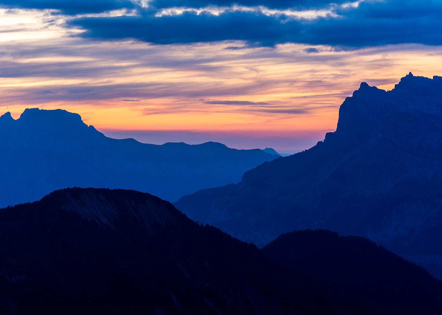 Viewed towards the setting sun from above Les Houches in the french alps, the distant Aravis mountains seen in this photograph create layers with the nearer mountains of the french alps
