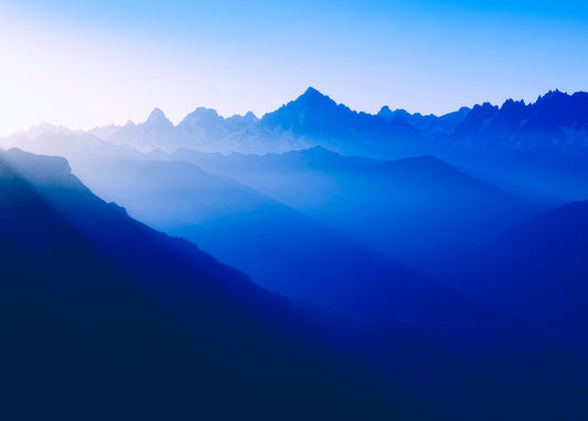 Photo of the rising sun casting golden rays across an alpine mountain landscape
