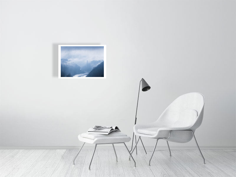 A white brick wall with a hanging picture of Clifton Suspension Bridge in the distance breaking free of the morning fog, with the River Avon below and the Avon gorge