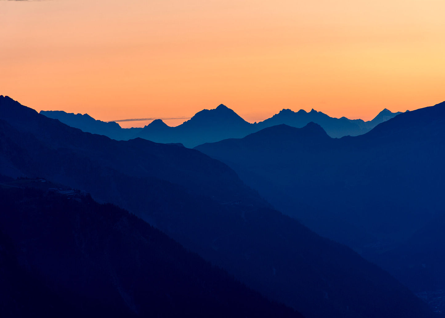 This Photograph captures stunning views of the sun setting behind the mountains of the Jura, revealing complex layers of as light rays light the sky in a magnificent display.