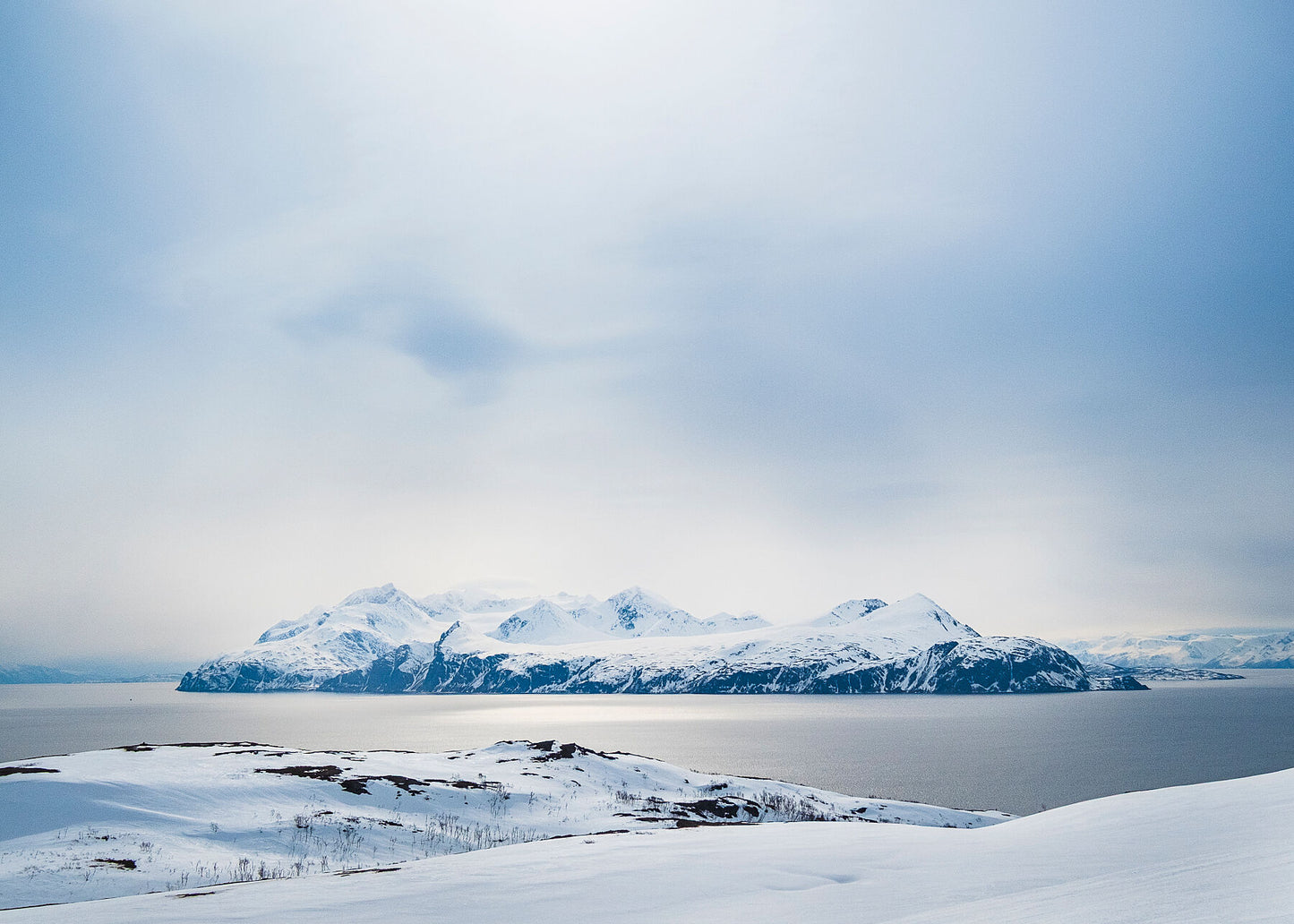 Golden sunlight reflects on the Fjord in Norway looking towards Lyngen Island