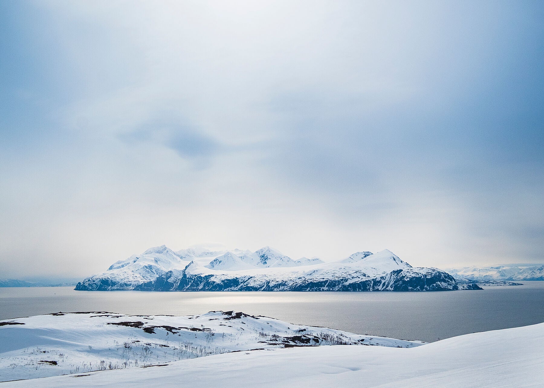 Golden sunlight reflects on the Fjord in Norway looking towards Lyngen Island