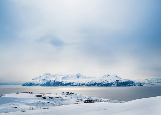 Golden sunlight reflects on the Fjord in Norway looking towards Lyngen Island