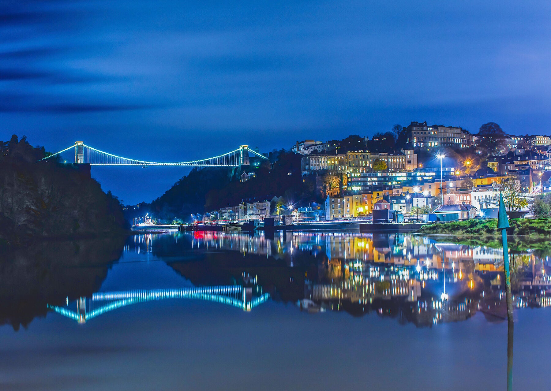 Clifton suspension bridge at night with an almost perfect reflection in the water of clifton village