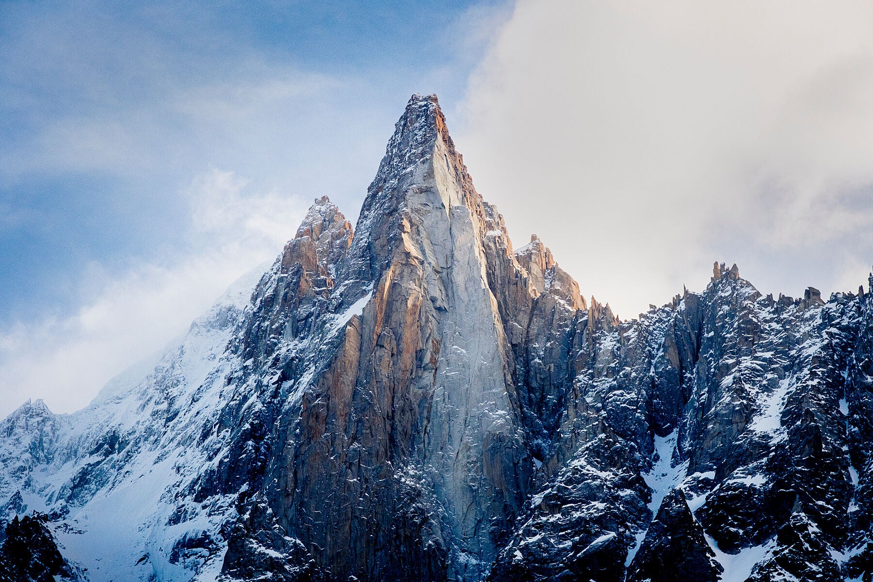 The distinctive Les Dru in the Mont Blanc Massif above chamonix, with snow covering the slopes and golden sunlight on the mountain