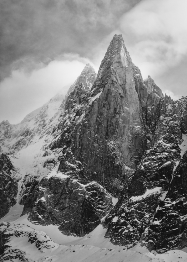 Les drus mountains in the mont blanc massif, with clouds swirling around the peaks and snow at the foot of the mountain
