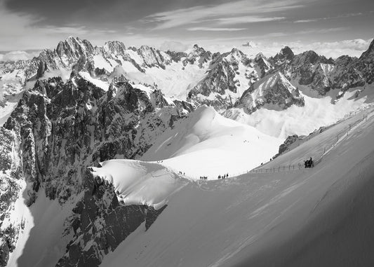 Skiiers descend the Arete leading to the Vallee Blanche with the mountains of the Mont Blanc Massif in the background