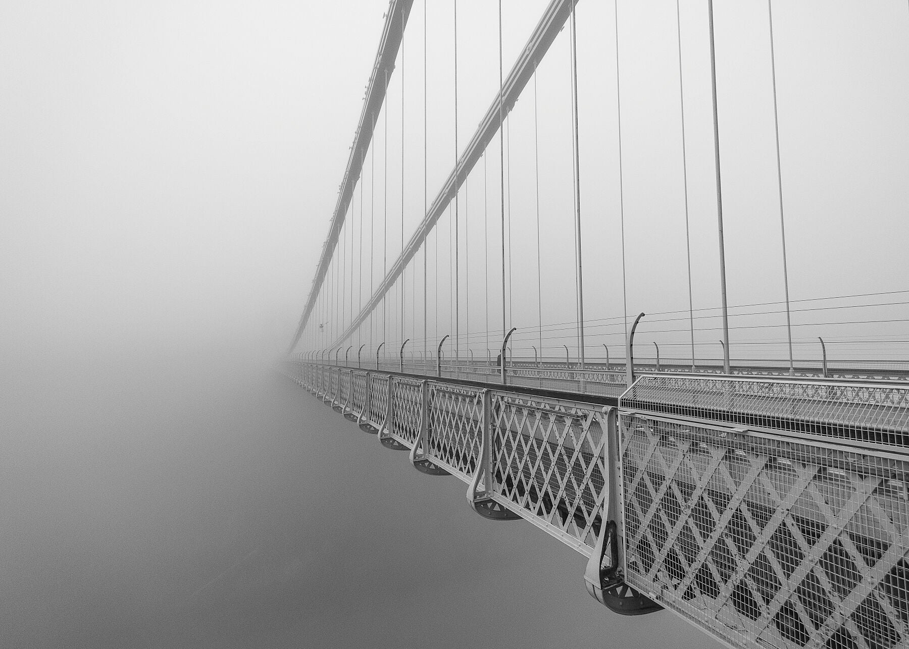 Clifton Suspension Bridge in Bristol receding into thick fog in black and white