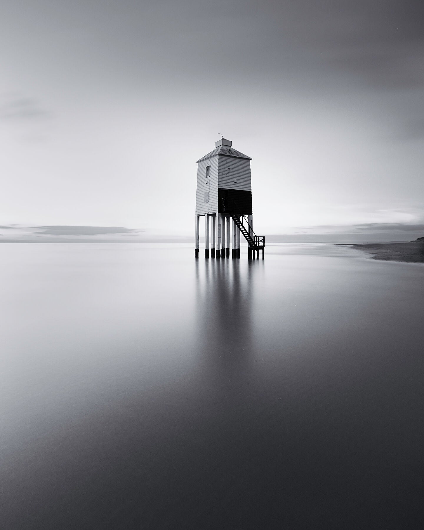 High tide sweeps across the sands surrounding the Burham Low lighthouse in the severn estuary, which stands isolated and proud in this beautiful black and white photograph