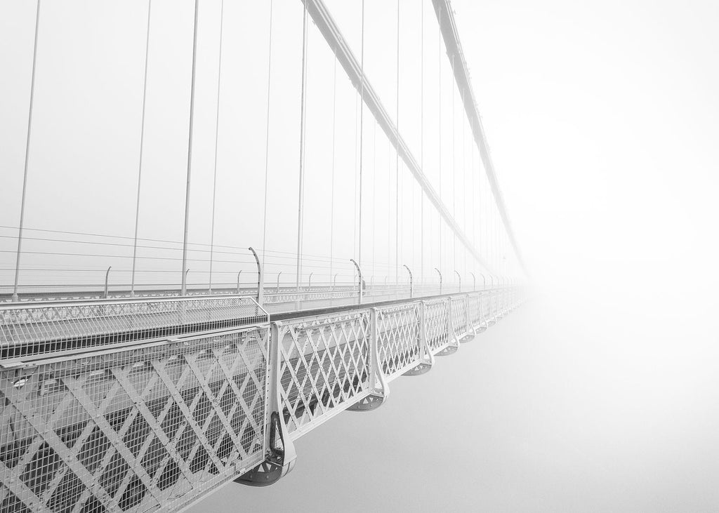 Black-and-white photograph of Clifton Suspension Bridge fading into fog