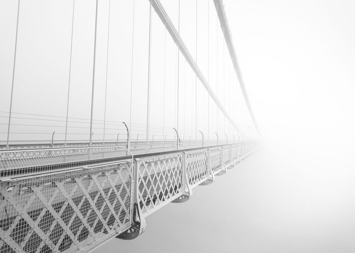 Black-and-white photograph of Clifton Suspension Bridge fading into fog