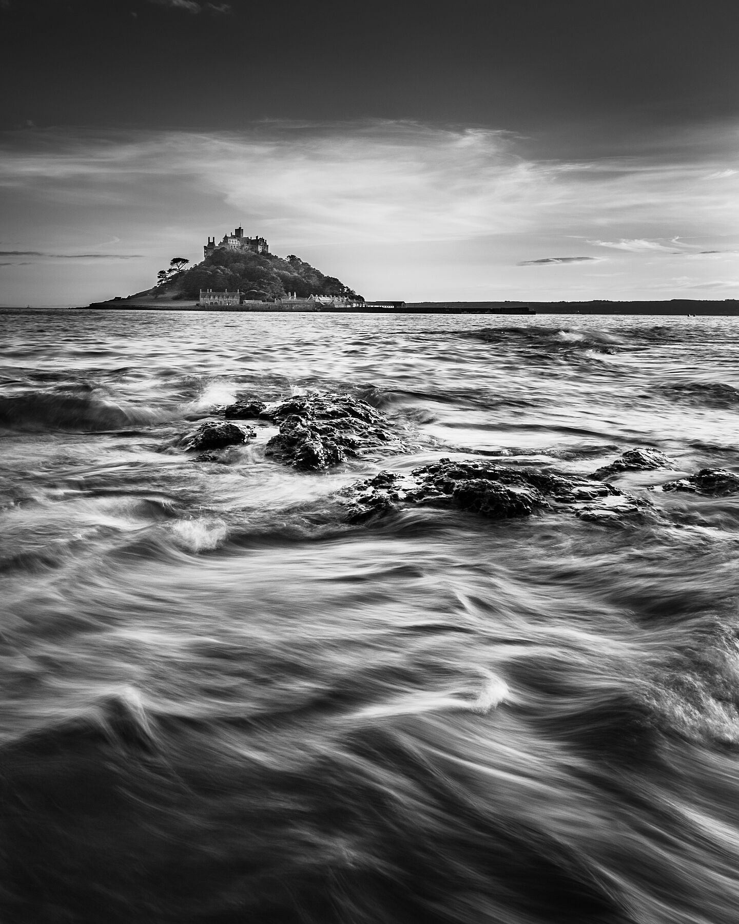 A beautiful black and white photograph capturing the movement of the sea leading towards the iconic St Michael's Mount in the background