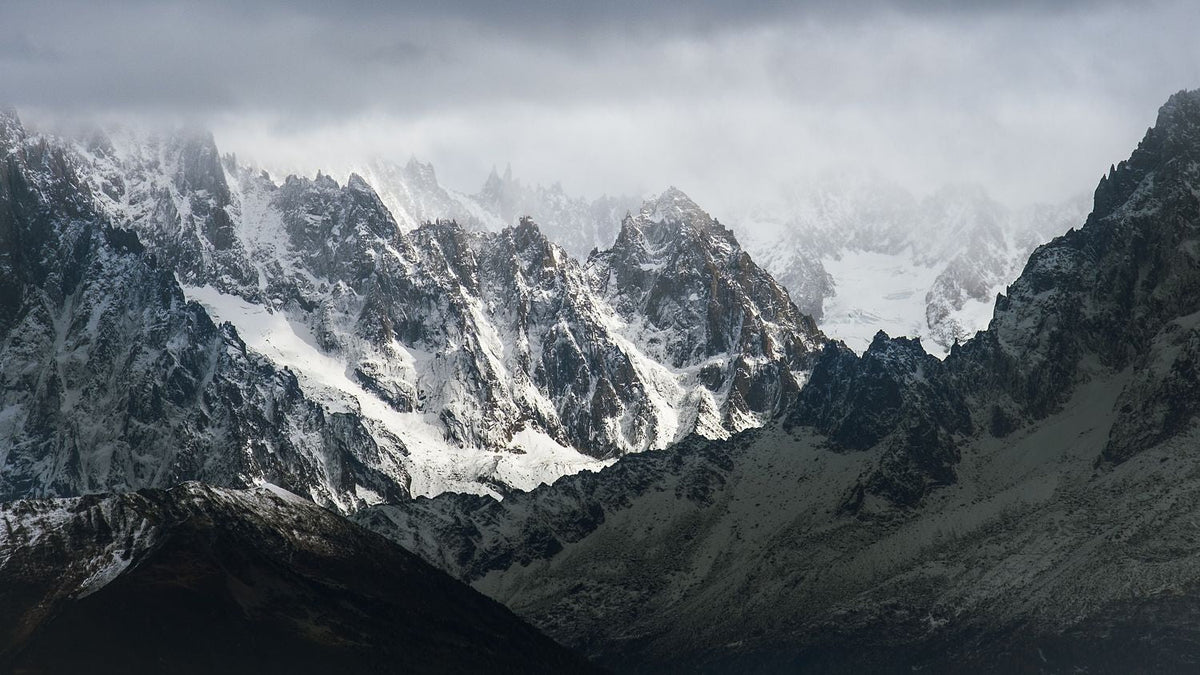 Snow-covered jagged peaks of the Mont Blanc massif emerging through low cloud near Chamonix.